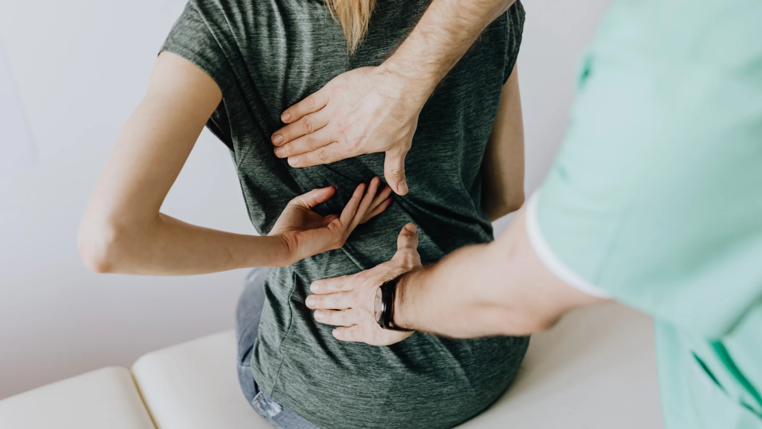 Une femme reçoit un massage du dos par un médecin pour soulager ses douleurs dorsales.